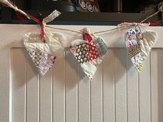 three pieces of cloth hanging from a line on the wall next to a stove top