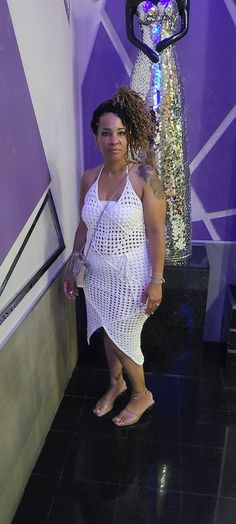 a woman standing in front of a purple and white wall next to a light fixture