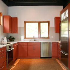 an empty kitchen with red cabinets and stainless steel appliances, including a dishwasher