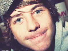 a close up of a person wearing a beanie and looking at the camera with a smile on his face