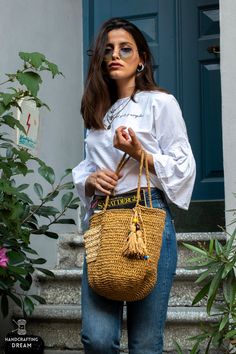 a woman is standing outside with her handbag in front of the door and looking off into the distance