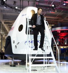 a man standing on top of a ladder next to a white space shuttle in a building