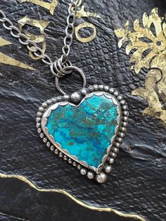 This is a turquoise and blue chrysocola with little bits of orange red heart shaped pendant surrounded by beaded wire inside a scalloped fine silver bezel. At top and bottom are handmade solid silver balls. The entire piece has an added dark patina. Comes with a chunky textured sterling silver chain with a patina. A nice substantial piece that has that wow factor. Comes gift boxed with a polishing pad.   All my pieces are completely handmade in my Colorado mountain studio and supervised by my th Blue Bohemian Heart Pendant Jewelry, Bohemian Blue Heart Pendant Jewelry, Spiritual Blue Jewelry With Heart Charm, Artisan Heart Shaped Jewelry For Crafting, Sterling Silver Heart-shaped Soldered Necklaces, Heart-shaped Sterling Silver Soldered Necklace, Sterling Silver Heart-shaped Soldered Necklace, Sterling Silver Heart Necklace With Soldered Details, Bohemian Turquoise Heart Pendant Jewelry