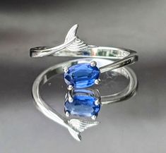 Stones have been tested by a professional and certified gemologist using professional equipment. Dive into Enchantment with Our Exquisite Blue Kyanite Mermaid Tail Ring - Channel Your Inner Mystical Beauty! 🌊 Awaken Your Inner Mermaid: Immerse yourself in the world of fantasy and elegance with our enchanting Blue Kyanite Mermaid Tail Ring. The intricate mermaid tail band wraps around your finger, capturing the allure of the ocean and igniting your inner mystique. 💎 Mesmerizing Blue Kyanite: Ad Adjustable Sapphire Ring Fine Jewelry, Adjustable Sapphire Ring In Fine Jewelry Style, Gia Certified Oval Topaz Ring For Gift, Gia Certified Oval Topaz Ring As Gift, Gia Certified Blue Topaz Ring, Kyanite Ring, Ocean Treasures, Symbols Of Freedom, Blue Kyanite