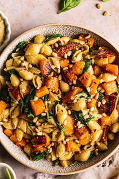 a white bowl filled with pasta and spinach on top of a table next to other dishes