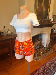 "\"Who wears short shorts?\"  These tiki shorts from the 1960s are so fun!  These flame-colored tiki-print hot pants are beach- and festival-ready. Fully lined; zip up the back. Wear with your favourite crop as pictured, or with a simple tee. In excellent vintage condition. Measurements: Waist: 13.5\"  Hip: 18\"" Multicolor Hawaiian Style Shorts, Hawaiian Shorts For Vacation, Hawaiian Style Shorts For Vacation, Multicolor Fitted Short Swim Trunks, Bohemian Short Length Swimwear For Vacation, Fitted Multicolor Swim Trunks, Bohemian Short Length Swimwear For Beach Season, Stretch Beachwear Shorts For Festival, Hippie Fitted Bottoms For Vacation