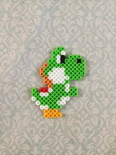 an image of a green frog made out of legos on a wallpapered surface