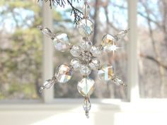 a snowflake ornament hanging from a christmas tree in front of a window