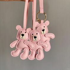 two teddy bears are attached to a pink leather key fobl with matching straps