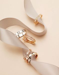 two gold rings with white satin ribbon on the side and one ring with diamonds in the middle