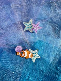 two little nemo fish pinbacks sitting on top of a blue netted cloth