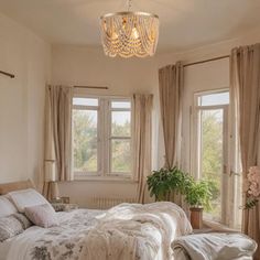 a bedroom with a large bed and chandelier hanging from it's ceiling