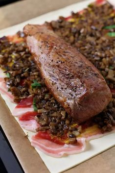 a large piece of meat sitting on top of a white plate covered in rice and other food