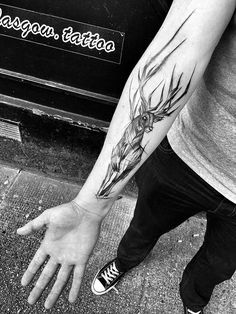 a man with a deer head tattoo on his arm holding onto the hand of another person