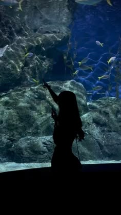 a woman pointing at fish in an aquarium