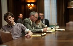 three men sitting at a table with papers and pens