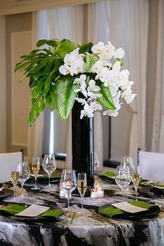 there is a vase with white flowers in it on top of a black table cloth