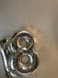 the number eight balloon is hanging from the ceiling in front of a white wall with silver foil