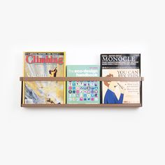 a wooden shelf holding books and magazines on it's sides, against a white wall