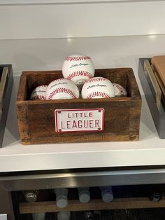 several baseballs are in a wooden box on the shelf next to an oven door