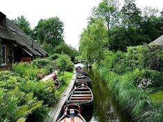 several boats are lined up on the side of a canal in front of some houses