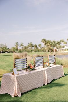 a table set up with chairs and signs for guests to sit at on the grass