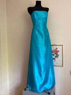 ♥ Vintage strapless maxi formal dress/gown - effortless luxury and elegance. ♥ The bust fitted with 4 bones, form-fitting.  ♥ Dramatic back pleat-short train. ♥ Color: vibrant turquois.  ♥ Polyester fabric.  ♥ Not lined, with zipper on the back. ♥ Good vintage condition, no major imperfections, only some minor signs of wear. I noticed some barely noticeable fraying on some seams, see last photo. ♥ Brand: Australian designer Ruth Tarvydas, who was famous for her exquisite high-end party dresses and ball gowns, which attracted tons of celebrities.  This find is very special to me, as a Lithuanian, and I loved doing some research: Ruth Tarvydas was born to Lithuanian parents, Martynas and Ursula Tarvydas. Ruth's first label, 'Ruta' (or Rūta, her original Lithuanian first name), was establishe Blue Strapless Floor-length Dress For Gala, Blue Floor-length Strapless Dress For Gala, Blue Fitted Strapless Floor-length Dress, Elegant Fitted Turquoise Maxi Dress, Blue Strapless Floor-length Dress For Formal Occasions, Blue Floor-length Strapless Dress For Formal Occasions, Strapless Green Maxi Dress For Wedding, Green Strapless Maxi Dress For Wedding, Blue Floor-length Strapless Formal Dress