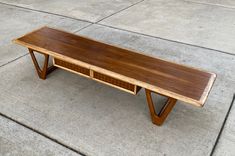 a wooden table sitting on top of a cement floor next to a sidewalk with no people