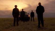 three men standing next to a truck in the middle of an open field at sunset