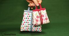 a hand holding two small bags with polka dots on them, one is red and the other is blue