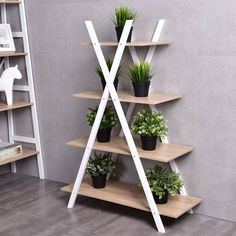 three tiered shelving unit with potted plants on each shelf in front of a gray wall