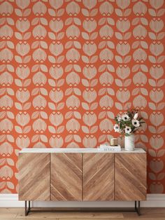 an orange and white wallpaper with leaves on it, next to a wooden cabinet