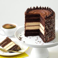 a chocolate cake with one slice cut out on a white plate next to a cup of coffee