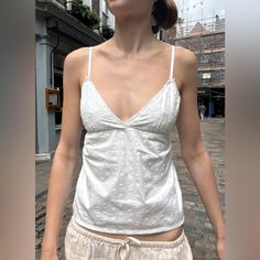 Flowy Tank Top With V-Neck, Floral Details, Adjustable Straps, And Tie In The Back Fabrics: 80% Polyester, 20% Cotton Measurements: Length: 16" (40cm) , Bust: 13" (33cm) Made In: China White V-neck Top For Summer, V-neck Camisole For Daywear, Fitted White Cotton V-neck Top, Spring V-neck Camisole For Daywear, Fitted V-neck Camisole, Cotton V-neck Tank Top, Fitted V-neck Tank Top For Daywear, Cotton V-neck Tank Top For Daywear, White Fitted V-neck Top For Summer