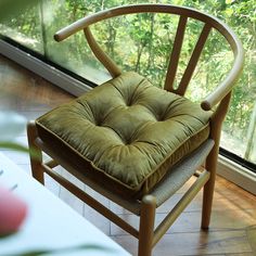 a chair with a cushion on it in front of a window