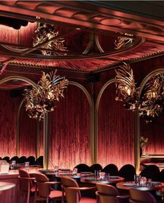 the interior of a fancy restaurant with chandeliers and red curtains on the walls