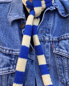 a blue and white knitted scarf tied to a jean jacket