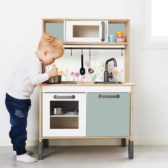 a little boy playing with a toy kitchen set