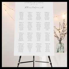 a white table plan sitting on top of a easel next to a vase filled with flowers