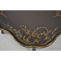 a black and gold painted table with ornate designs