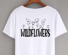 a white t - shirt with wildflowers printed on the front and black letters across the chest