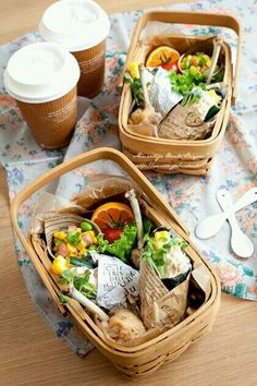 two baskets filled with food sitting on top of a table next to cups and utensils