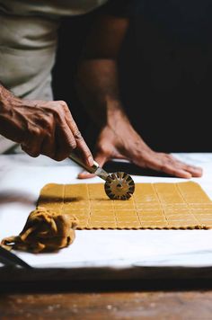 a person cutting some food with a knife on top of a white plate and yellow cloth