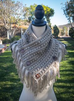 a mannequin wearing a scarf with buttons and fringes