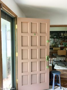 an open pink door in the middle of a room with stools and tables behind it