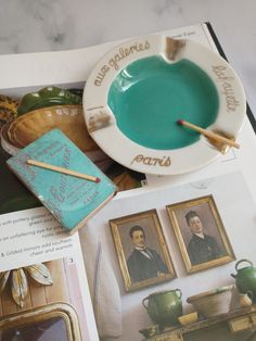 an open book with pictures and paintings on it's pages, including a teal saucer