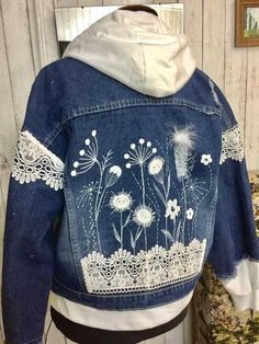 a denim jacket with white lace and flowers on it