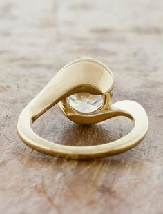 a gold ring sitting on top of a wooden table with a diamond in the middle