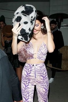 a woman in purple and white outfit holding up a pillow to her face while standing next to other people