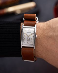 This vintage Longines timepiece embodies the elegance of the Art Deco era with its sleek 25 mm x 36 mm rectangular case, showcasing clean lines and timeless design. The silver dial is adorned with bold gold-tone Arabic numerals and minimalist golden hands, a hallmark of the Art Deco aesthetic. The subdial for seconds at 6 o'clock adds both functionality and a touch of geometric precision, typical of the era's style.  The watch's Art Deco case is complemented by a brown leather strap, which bring Vintage Rectangular Chronometer Watch, Timeless Rectangular Watch, Art Deco Rectangular Quartz Watch, Timeless Rectangular Chronometer Watch, Vintage Rectangular Dial Watch Accessories, Classic Jewelry And Watches With Chronometer Rectangular Dial, Vintage Rectangular Watch Accessories With Diamond Hour Markers, Classic Watch Bands For Anniversary, Retro Rectangular Watches For Formal Occasions